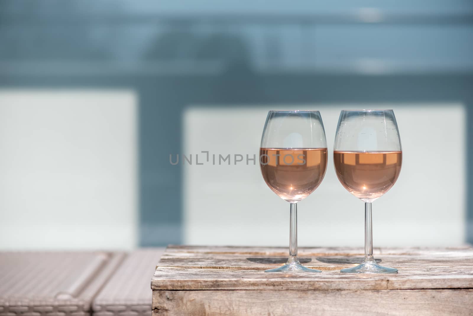 Two glasses of rose wine on a wooden table in sunlight