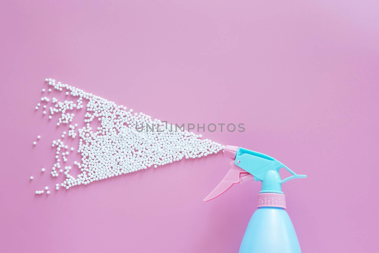 blue spray bottle spraying white bubble foam on pink background with copy space. creative minimal for cleaning concept by asiandelight