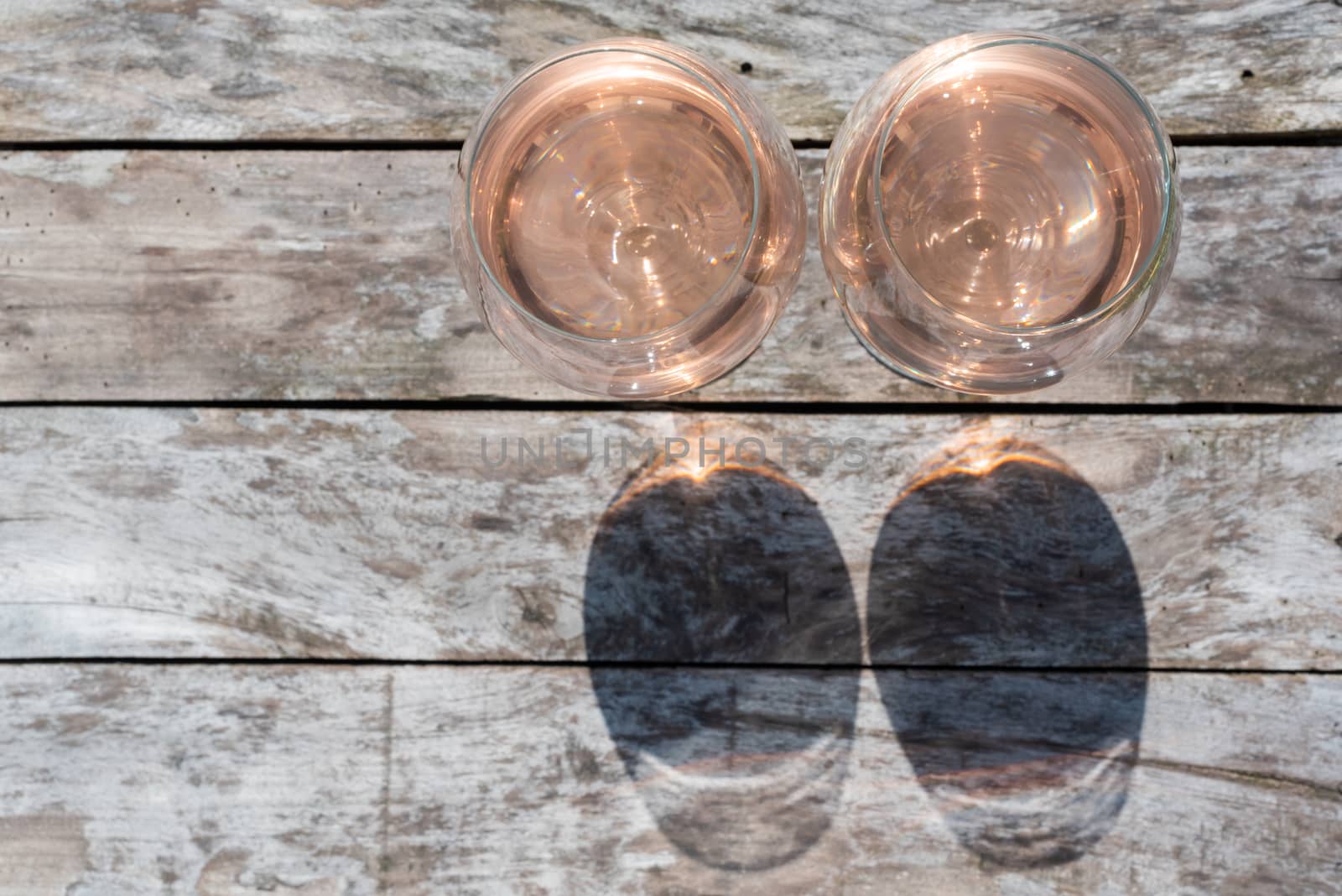 Two glasses of rose wine on a wooden table by LP2Studio