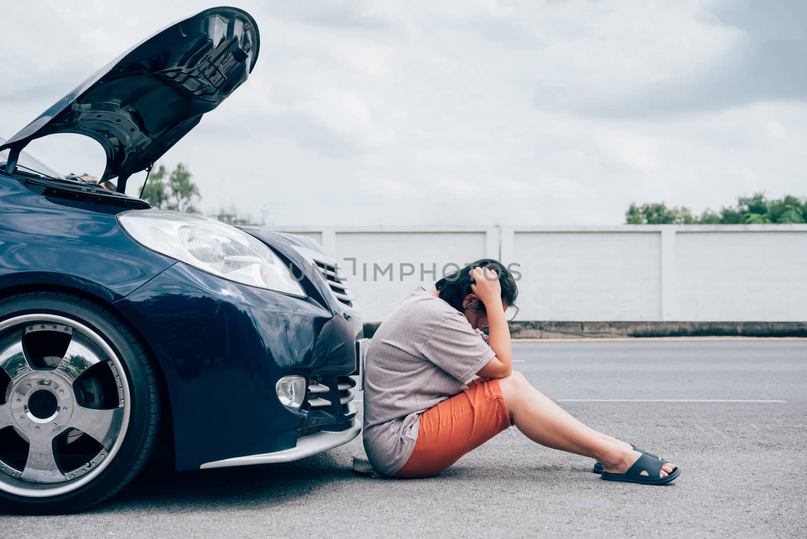 Asian woman 40s alone driver checking a car engine for fix and repair problem with unhappy and dismal between waiting a car mechanic from car engine problem at roadside