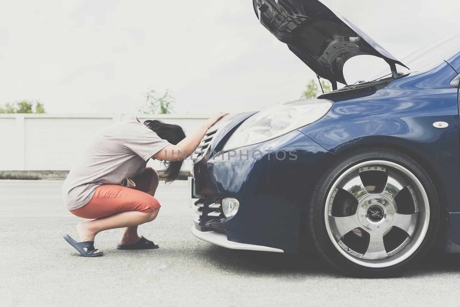 Asian woman 40s alone driver checking a car engine for fix and repair problem with unhappy and dismal between waiting a car mechanic from car engine problem at roadside