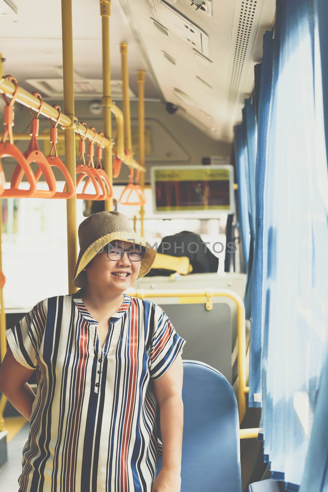 Asian woman 40s people travel by passenger bus in Bangkok city. Buses are one of the most important public mass transport system in Bangkok