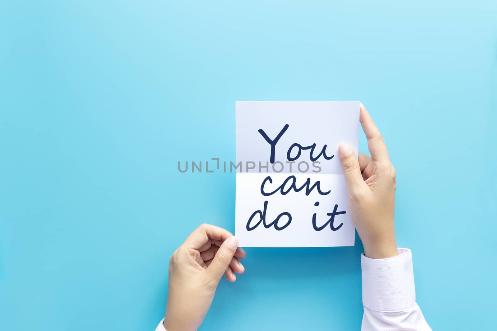 woman hand holding card with the word you can do it isolated on blue background, studio shot. cheer and support quote by asiandelight