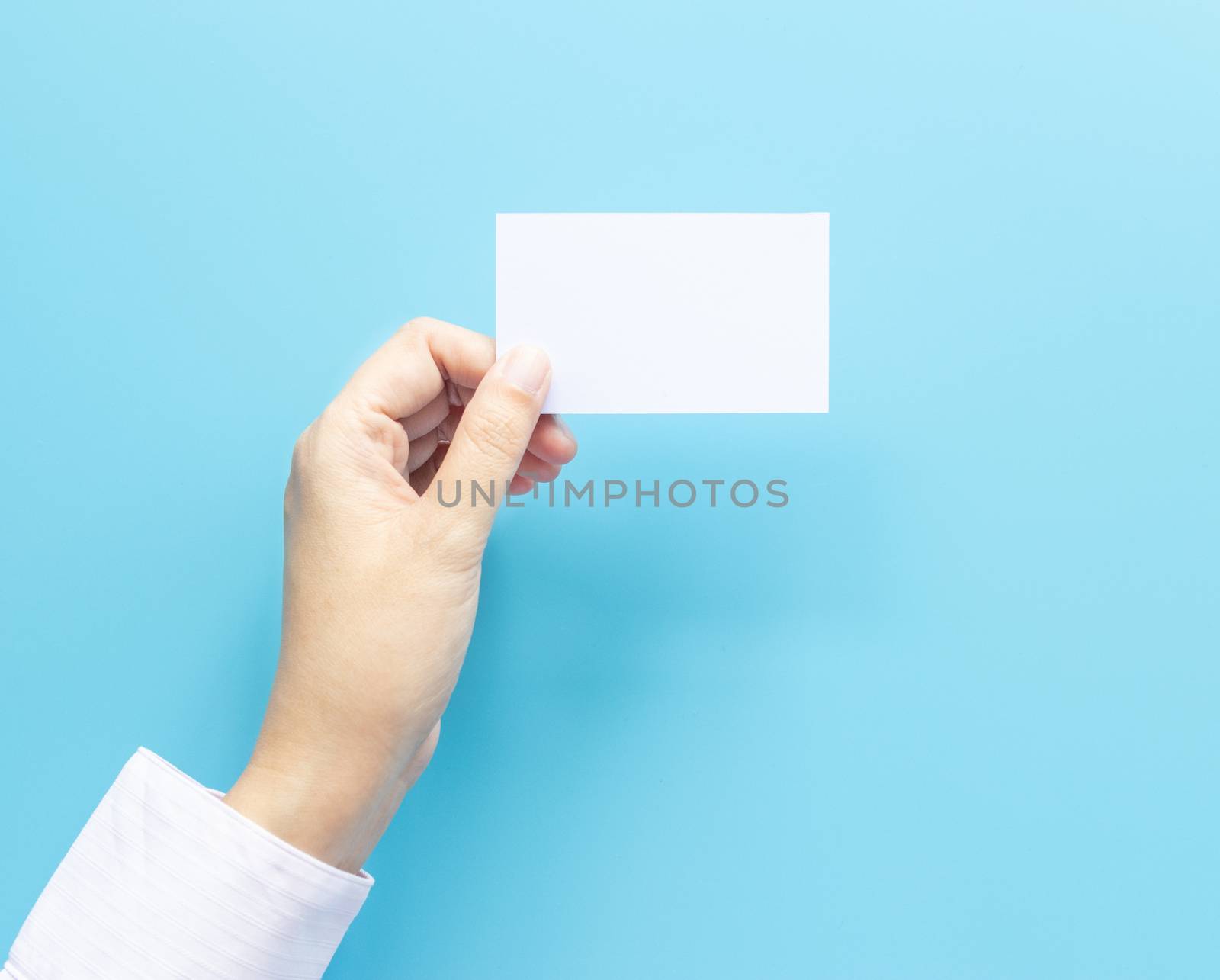 woman hand holding blank business name card paper isolated on blue background with copy space. by asiandelight