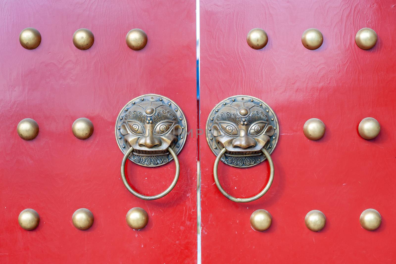 Golden colored chinese door knockers on a red gate