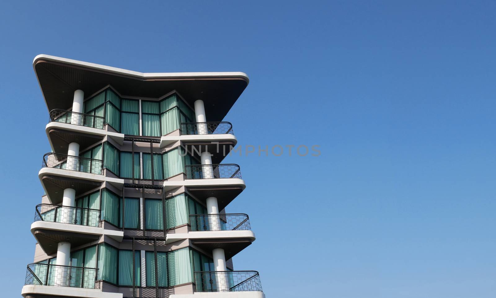 high modern, luxury apartment building with blue sky at background by asiandelight
