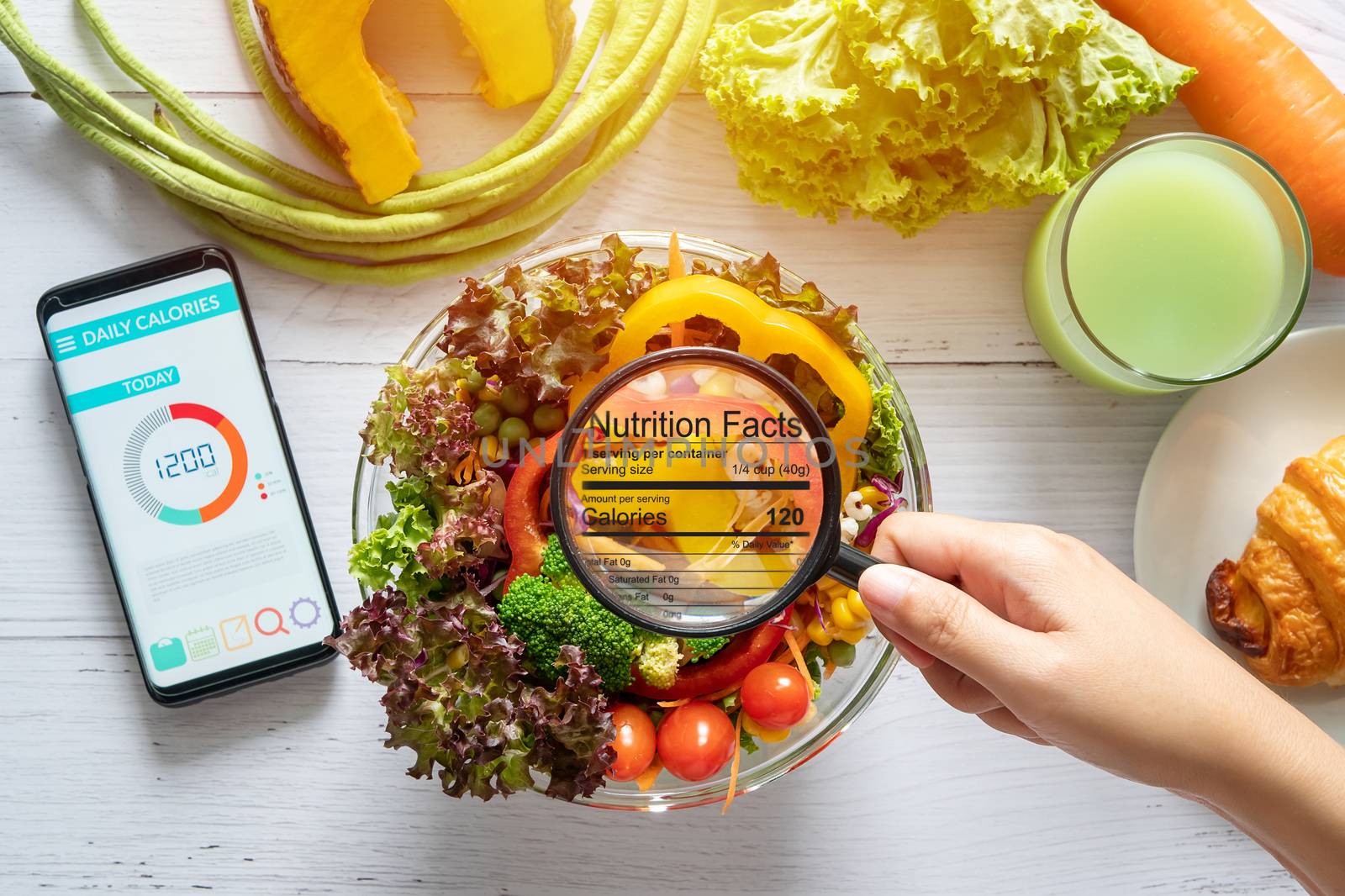 nutritional information concept. hand use the magnifying glass to zoom in to see the details of the nutrition facts from food , salad bowl by asiandelight
