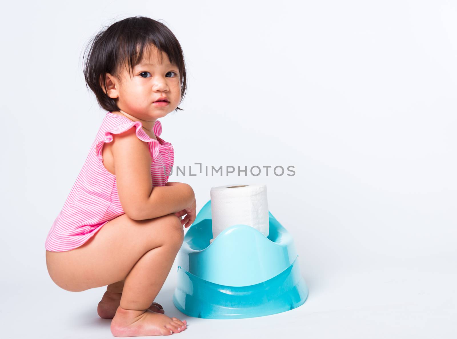 Asian little cute baby child girl education training to sitting on blue chamber pot or potty with toilet paper rolls, studio shot isolated on white background, wc toilet concept