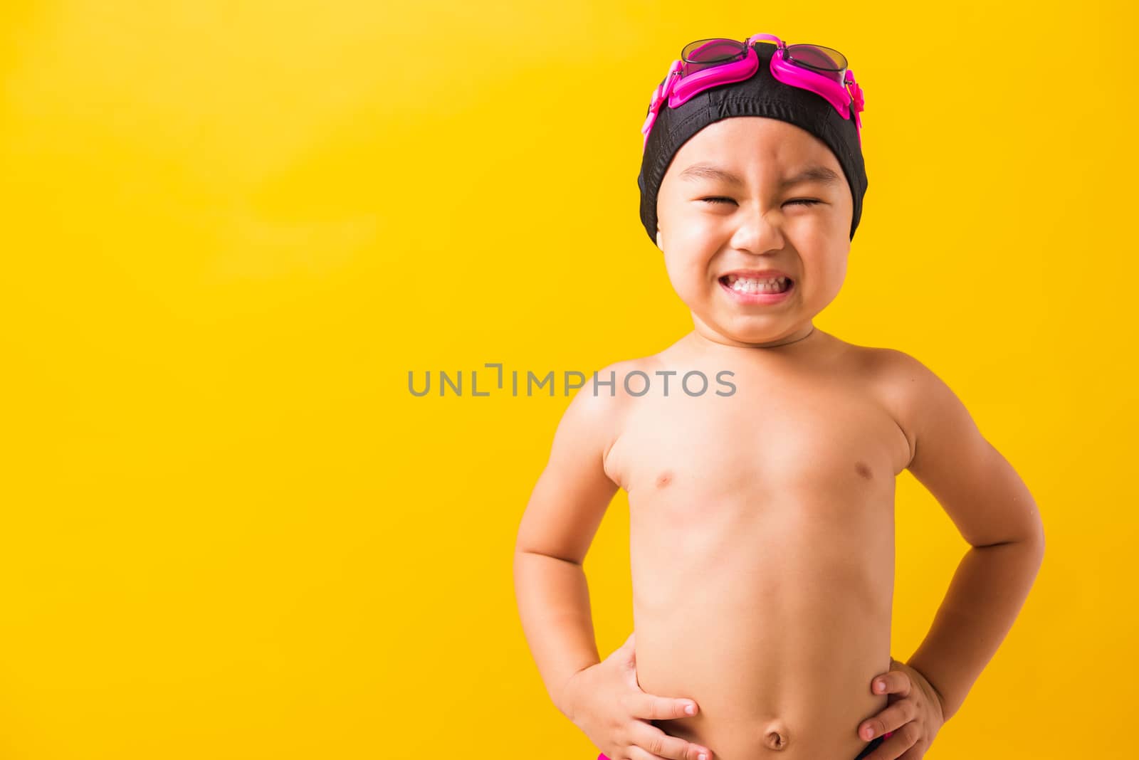 Summer vacation concept, Closeup portrait Asian happy cute little child boy wearing goggles and swimsuit, Kid having fun with in summer vacation looking camera, studio shot isolated yellow background