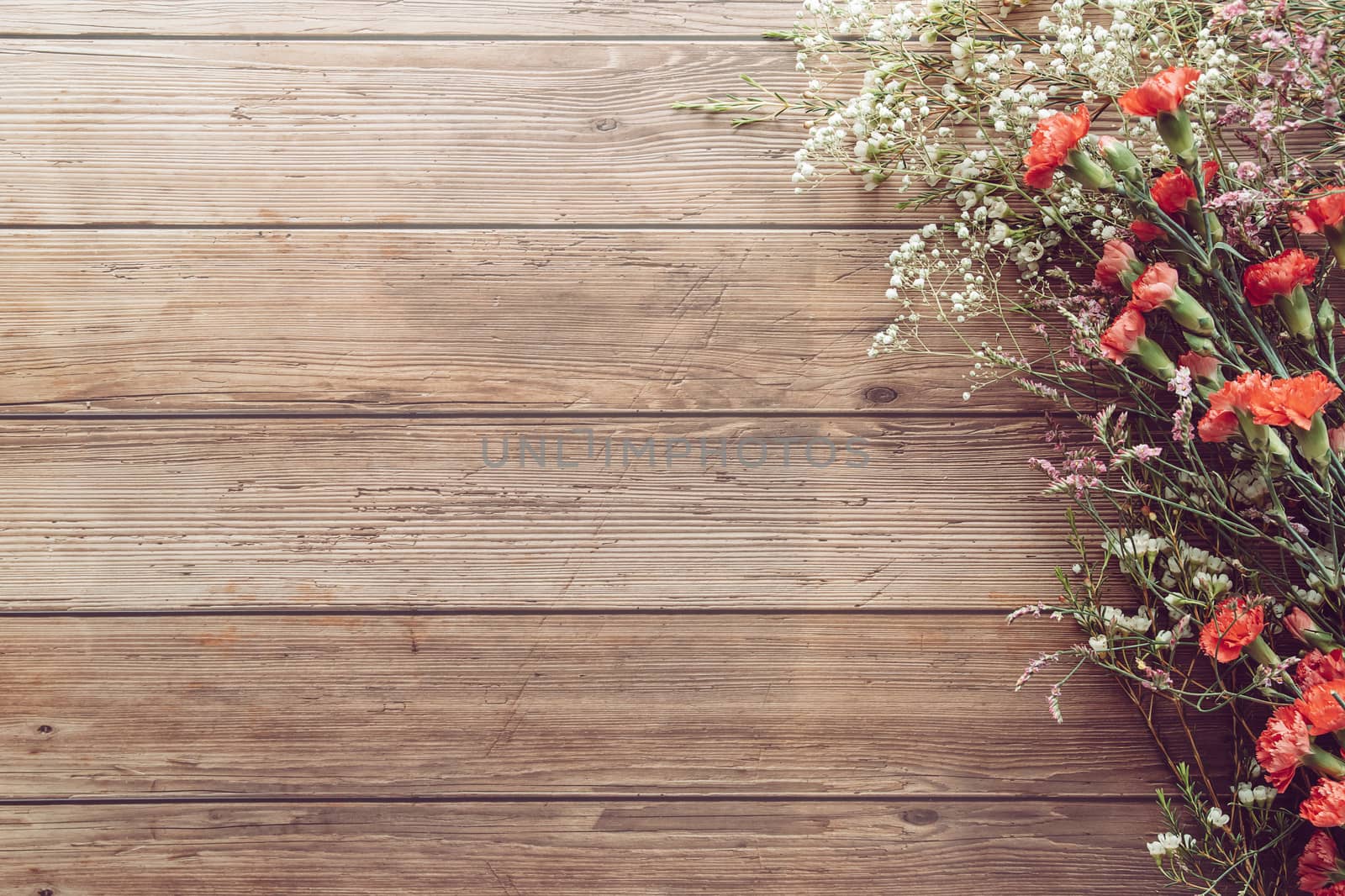 flat lay of garden spring white and red tiny flowers on wooden plank table background with copy space, retro color style by asiandelight