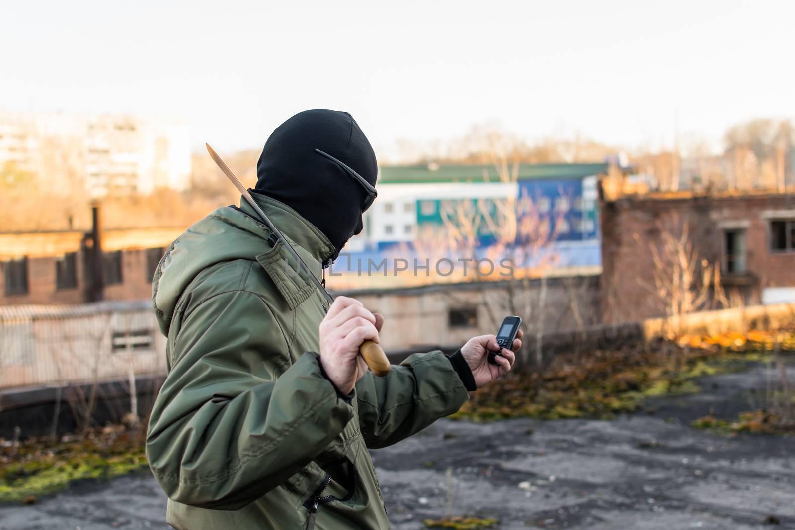 Criminal with a large knife looks into the phone