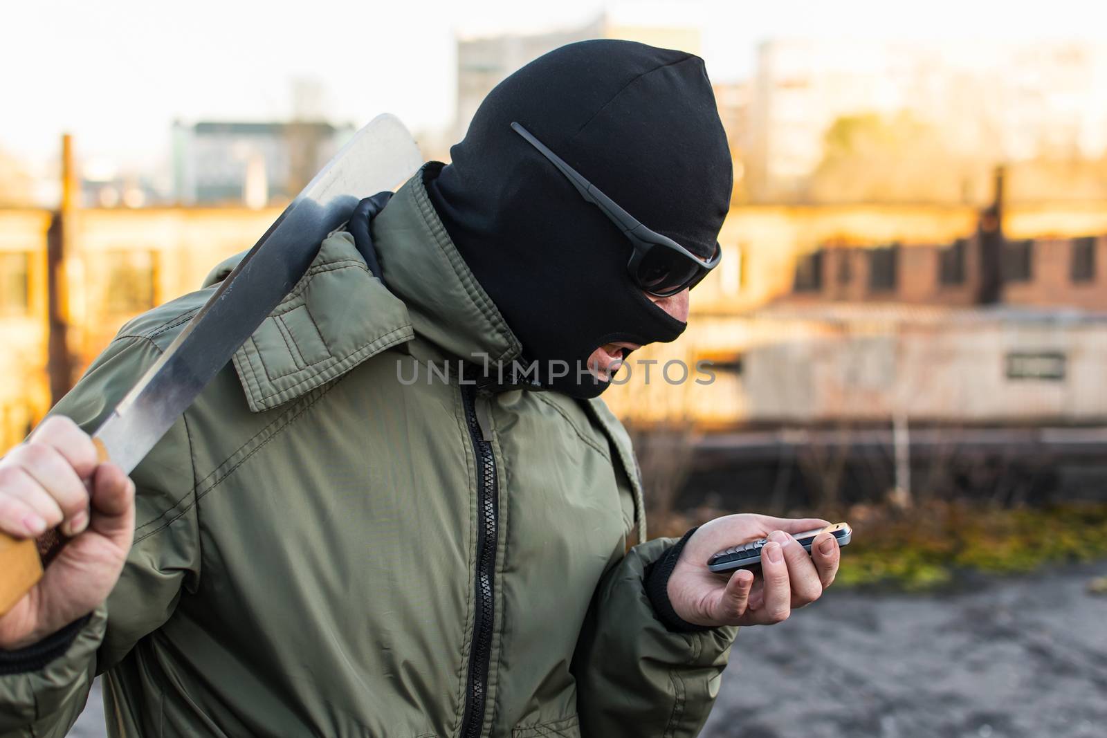Criminal in a mask in a rage looks at the phone