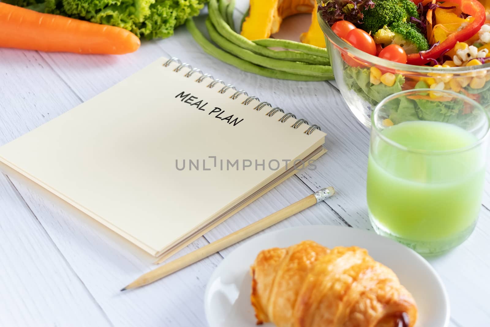 Calories control, meal plan, food diet and weight loss concept. meal plan writing on notebook planner with salad, fruit juice, bread and vegetable on dining table by asiandelight