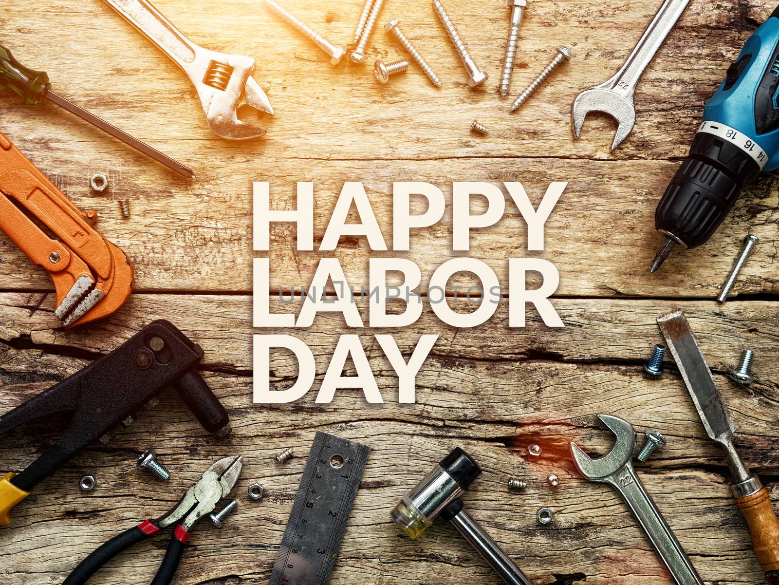 Happy Labor day text in white color on wooden background with construction repair tools.