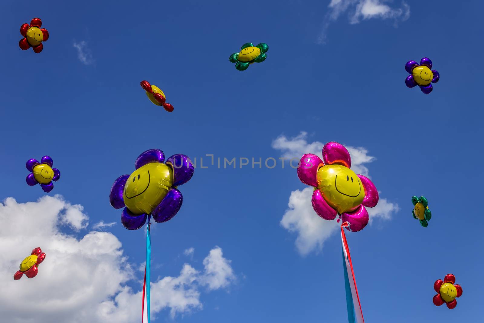 Balloons of different colors with smiles in the sky against the background of clouds