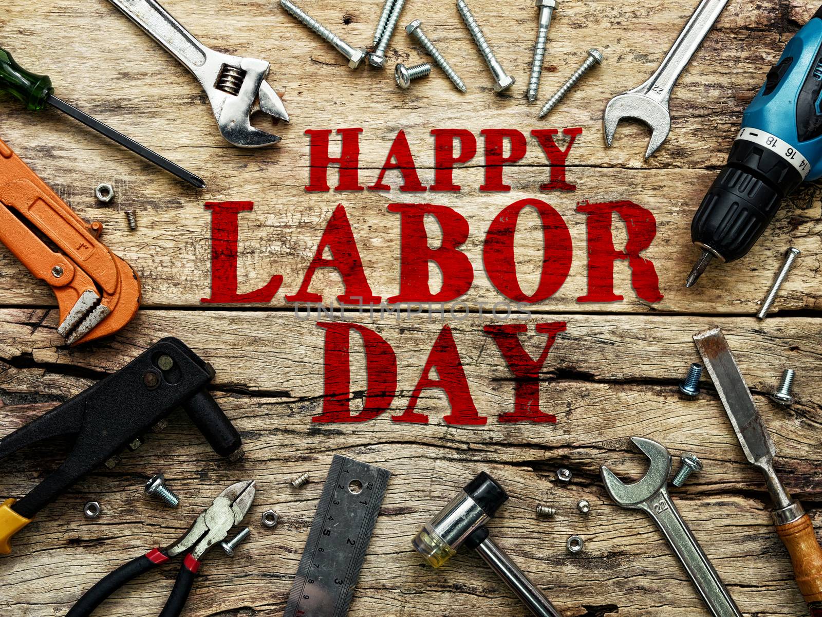 Happy Labor day text in red color on wooden background with construction repair tools.