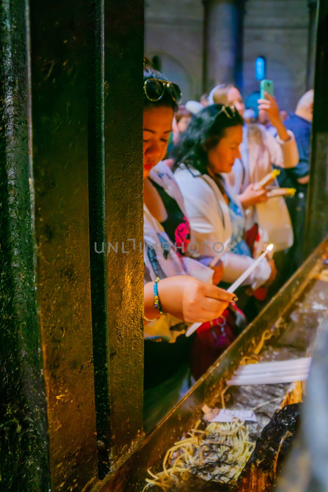 JERUSALEM, ISRAEL - APRIL 29, 2016: An Orthodox Good Friday scene in the church of the Holy Sepulcher, with women pilgrims lighting candles. The old city of Jerusalem, Israel