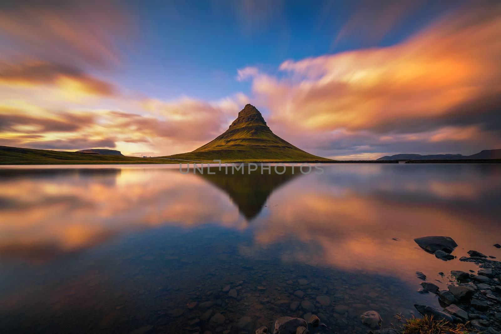 Sunset over Kirkjufell mountain with reflection in a nearby lake in Iceland by nickfox
