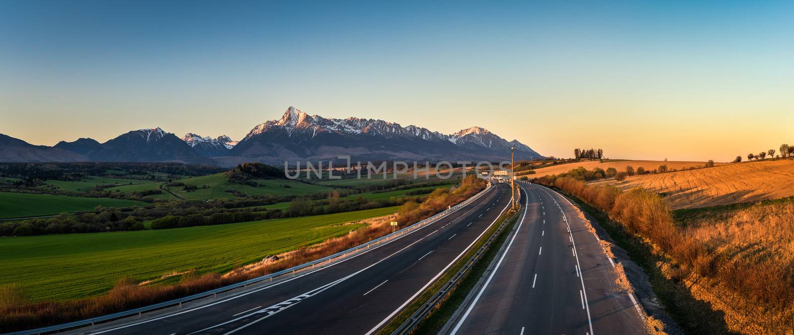 Panorama view of the High Tatra mountains with mount Krivan and a local highway in Slovakia at sunset