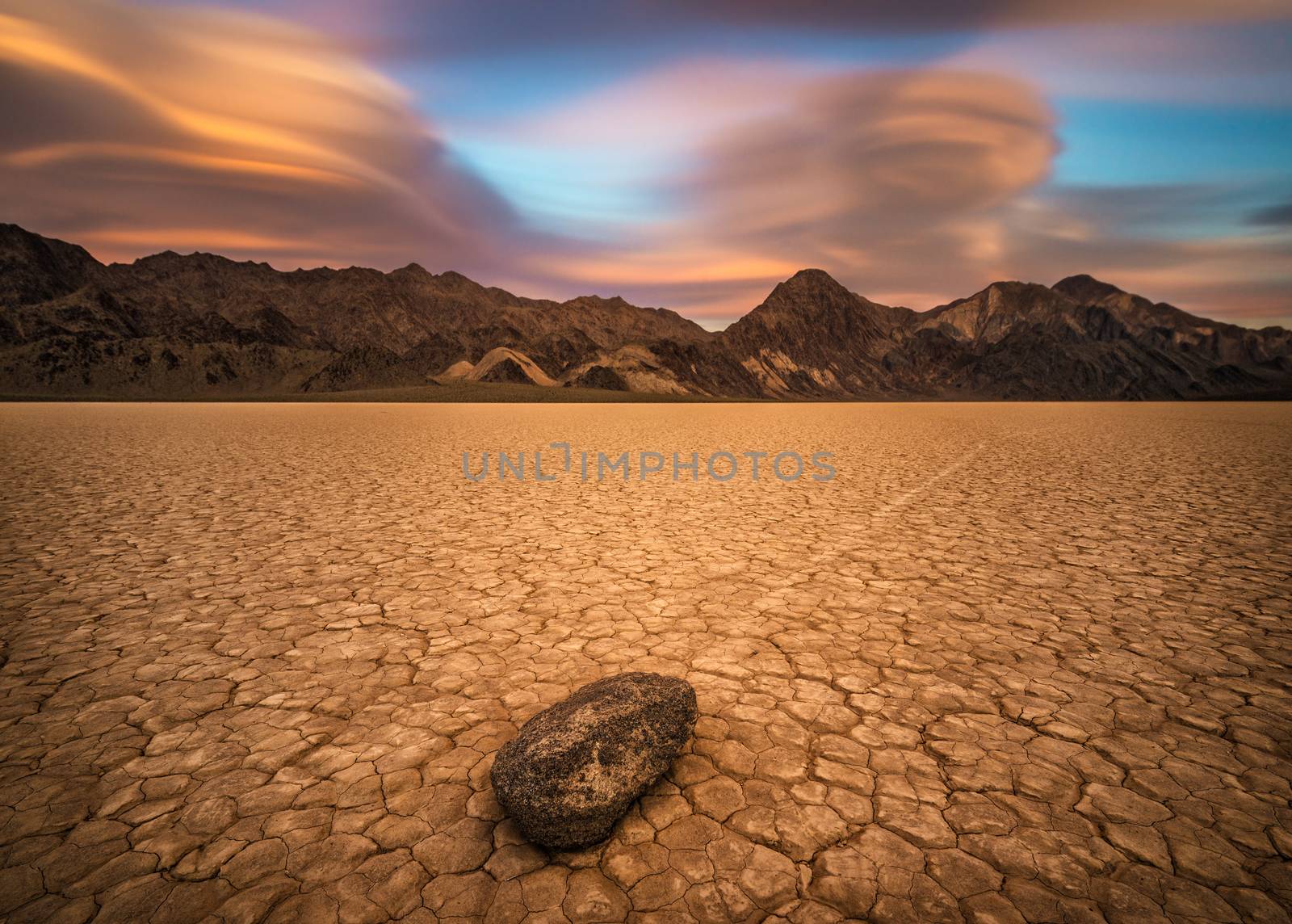  Sailing stone on the The Racetrack Playa in Death Valley National Park at sunset. The Racetrack Playa is a scenic dry lake with moving stones that inscribe linear imprints. Long exposure.