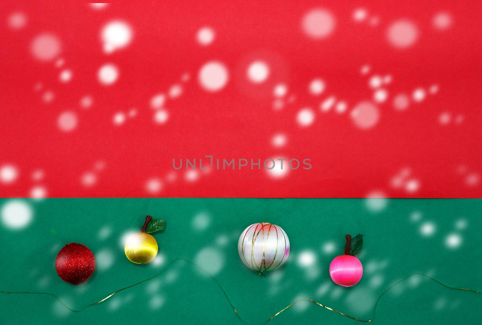 Baubles and fruits with golden string on green and red background for christmas with copy space with snow fall