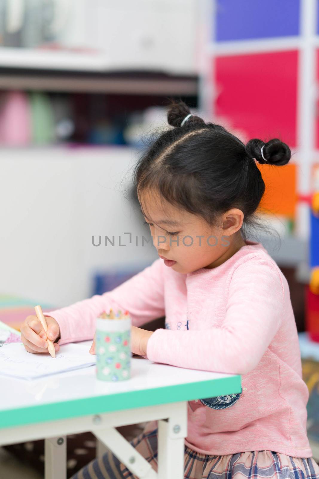 cute asian thai girl child kid sit and draw coloring homework on table happy cheerful