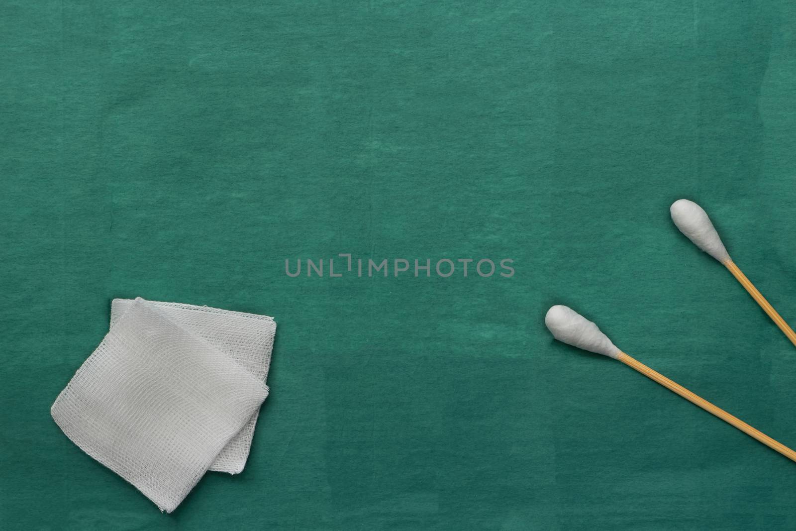 Gauze and swab cotton bus sticks on green medical surgical dress with copy space