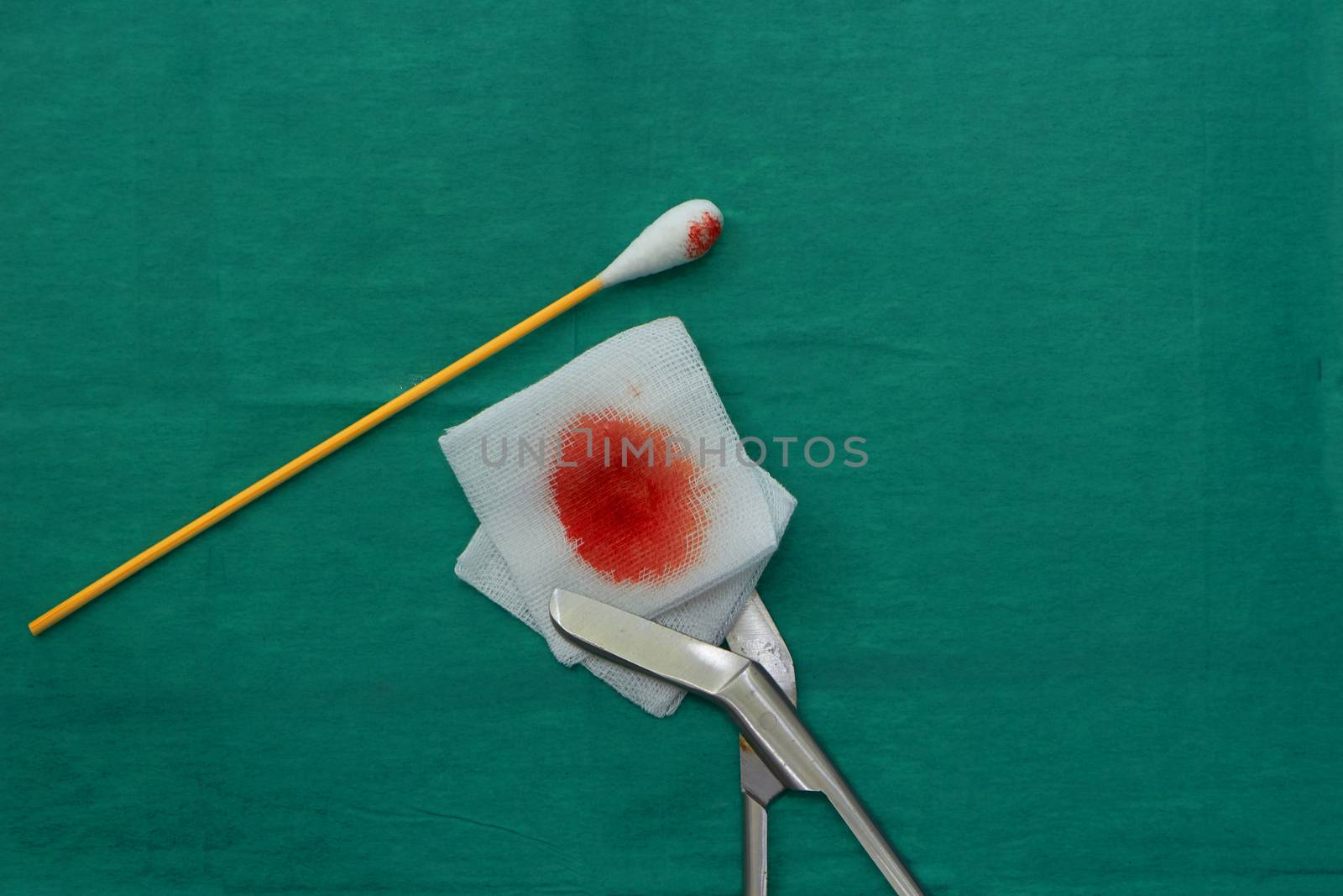 Gauze,blood,scissors and swab cotton bus sticks on green medical surgical dress with copy space