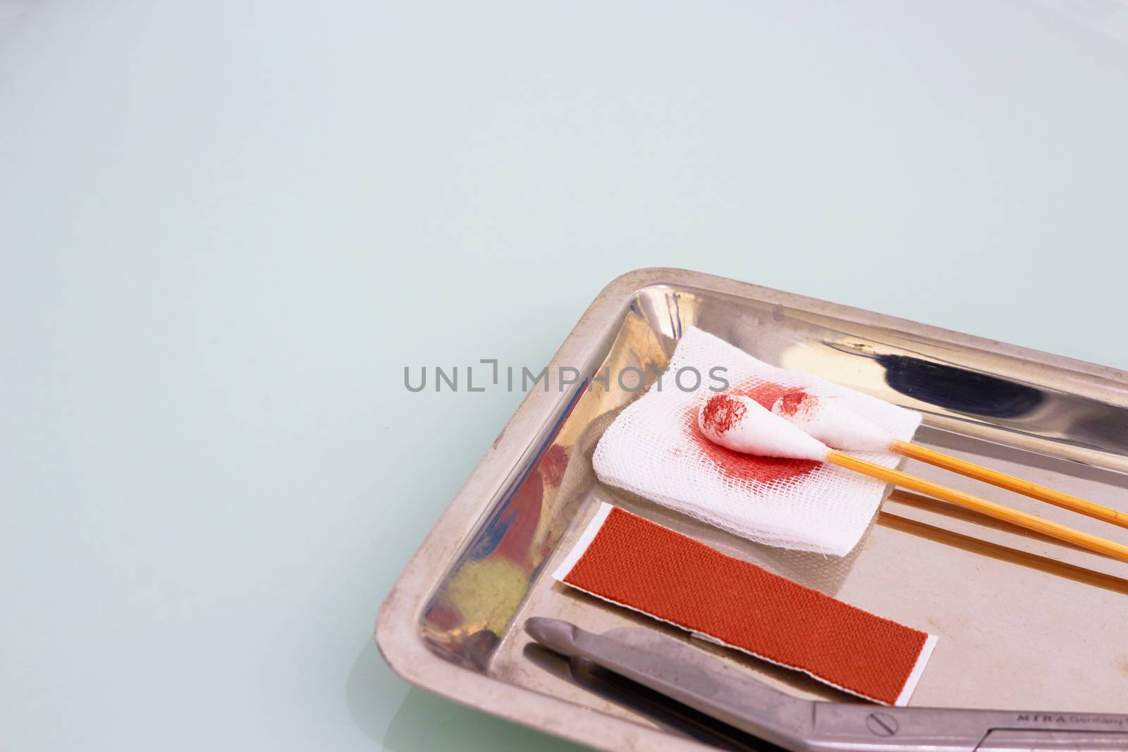 Gauze,blood,scissors,roll gauze ,plaster and two swab cotton bus sticks in medical surgical tray and copy space