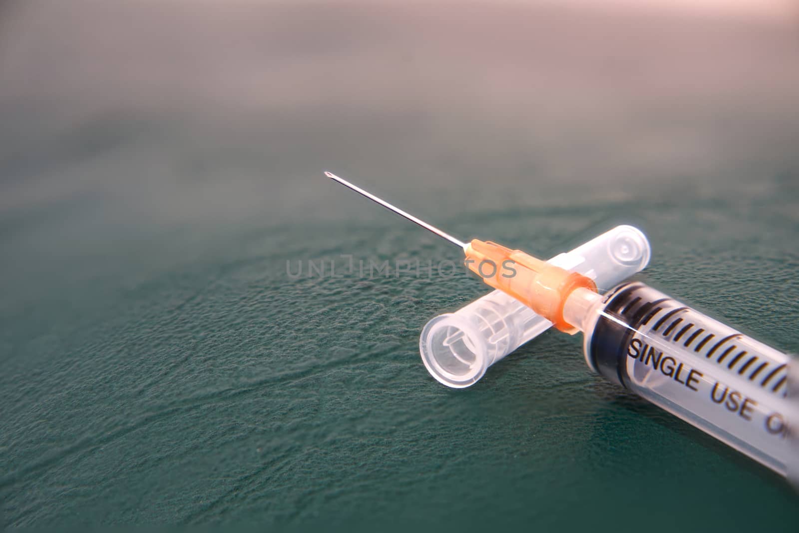 Medical care in syringe on cap and drug ampule broken in treatment hospital concept on green floor