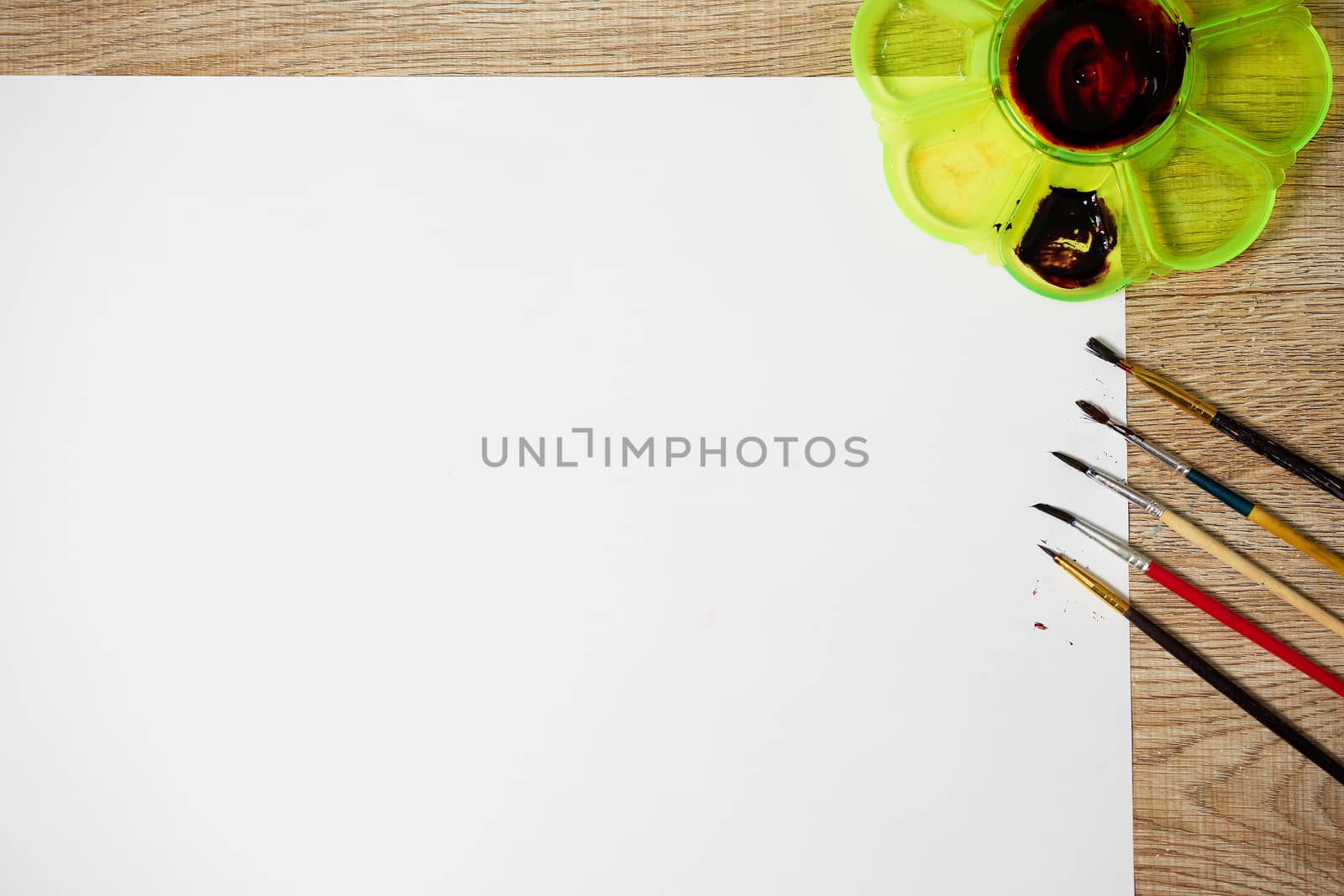 Paper of art work with color plate and color brushes, top view