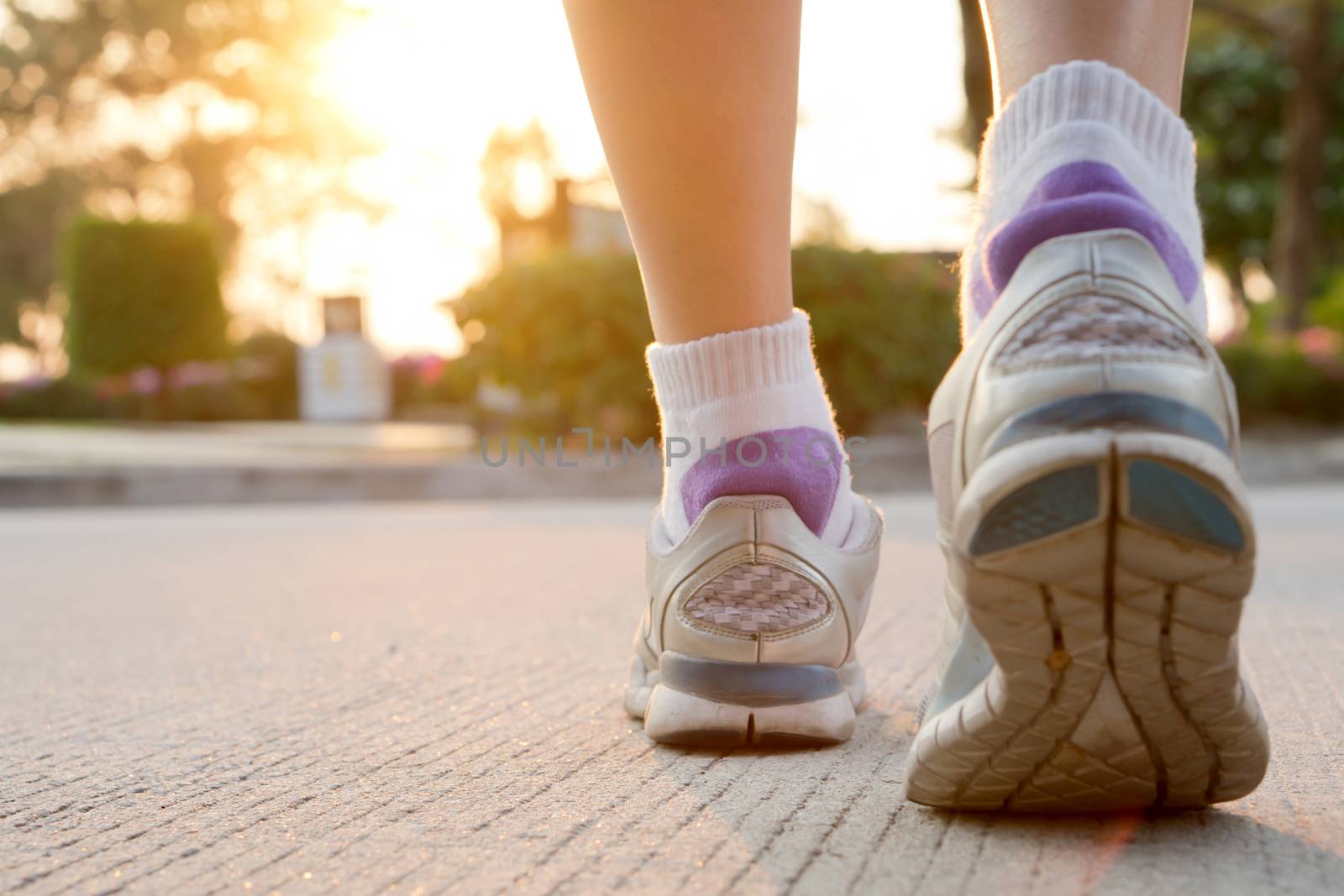 Runner feet running on road closeup on shoe. woman fitness sunrise jog workout welness concept.