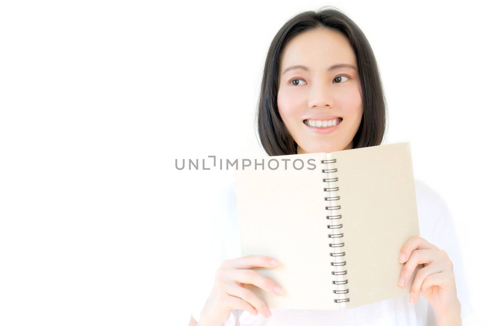 White girl smile and hides his face behind a book. Studio portrait of blonde model