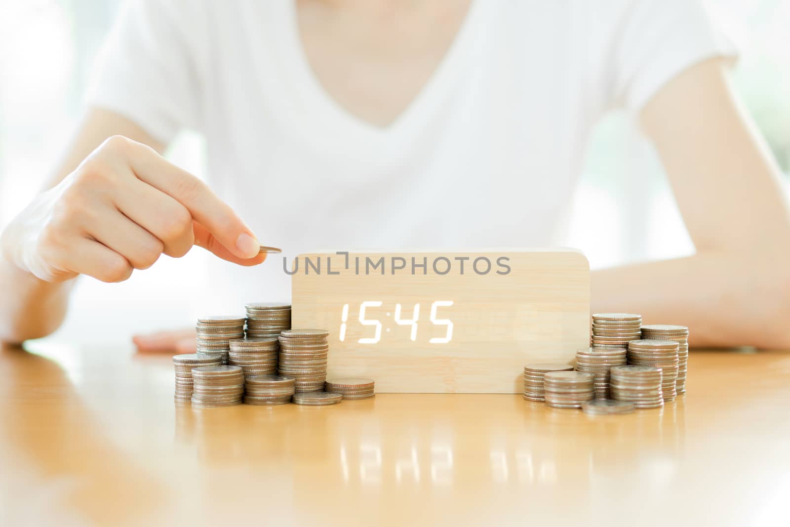 Close up of female hand stacking gold coins isolated on white background