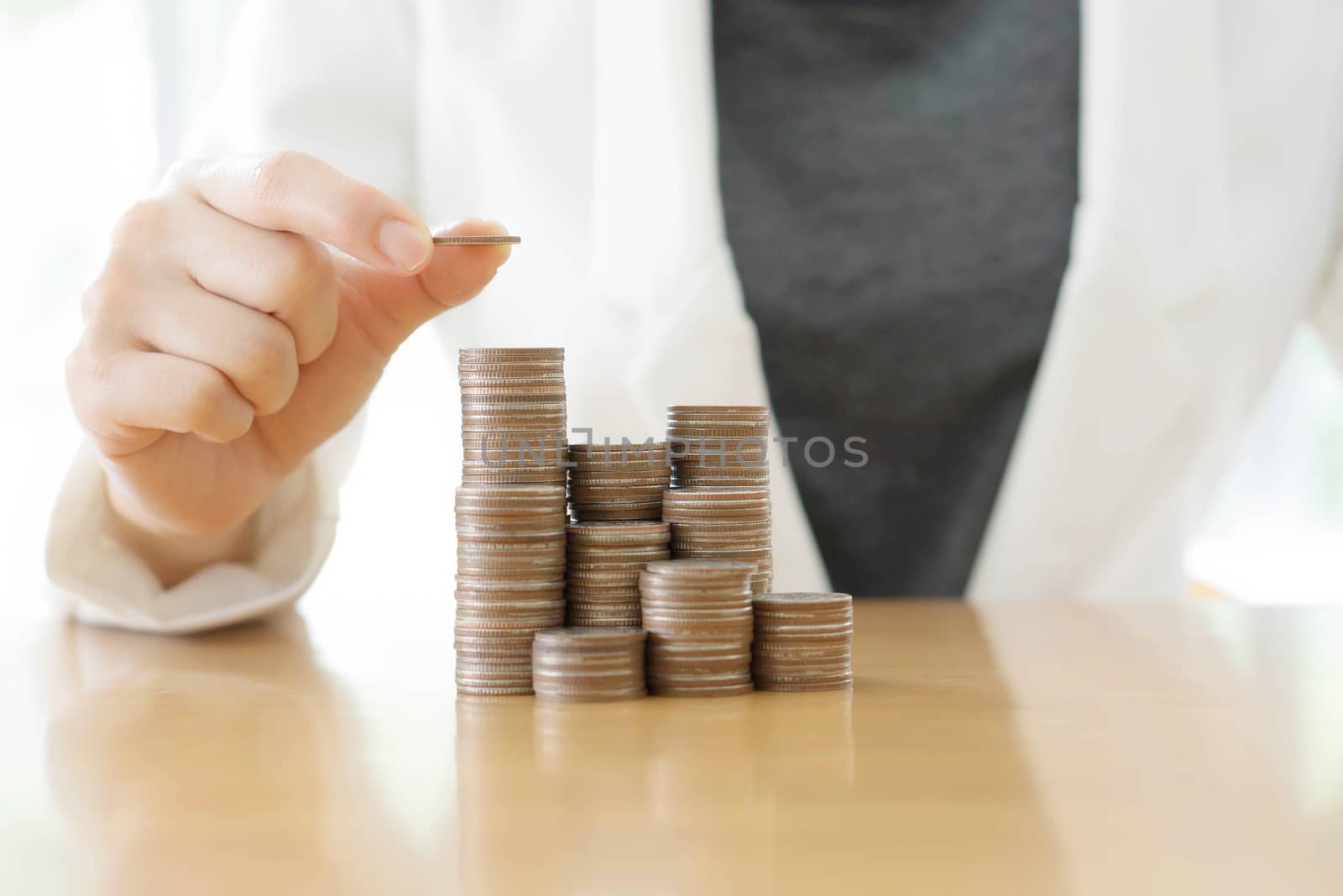 Close-up Of Businesswoman Placing Coin Over Stack Of Coins