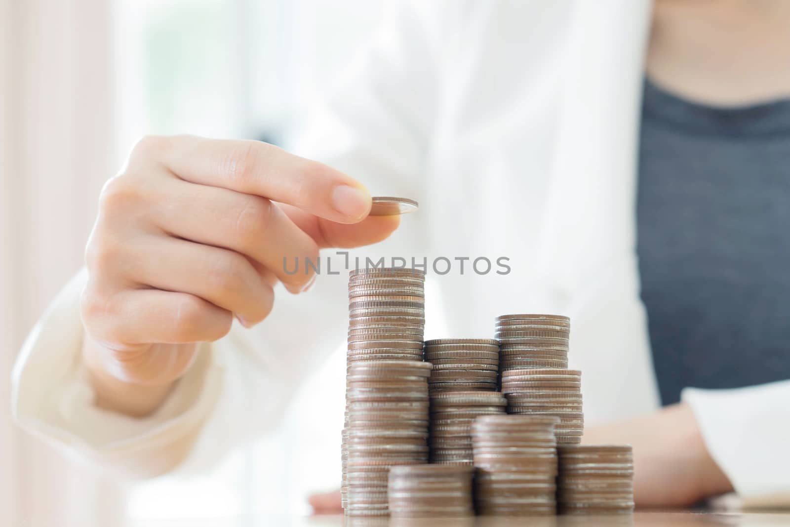 Close-up Of Businesswoman Putting Coin To Rising Stack Of Coins