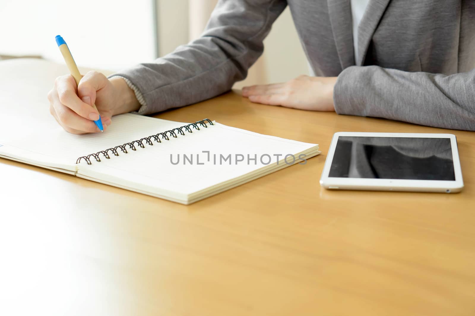 Woman hands with tablet PC and notepad at office by ekachailo