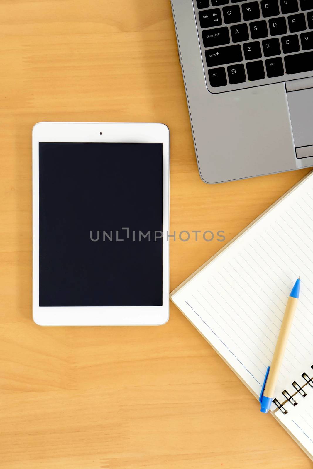 top view image of tablet device, paper note over wooden background