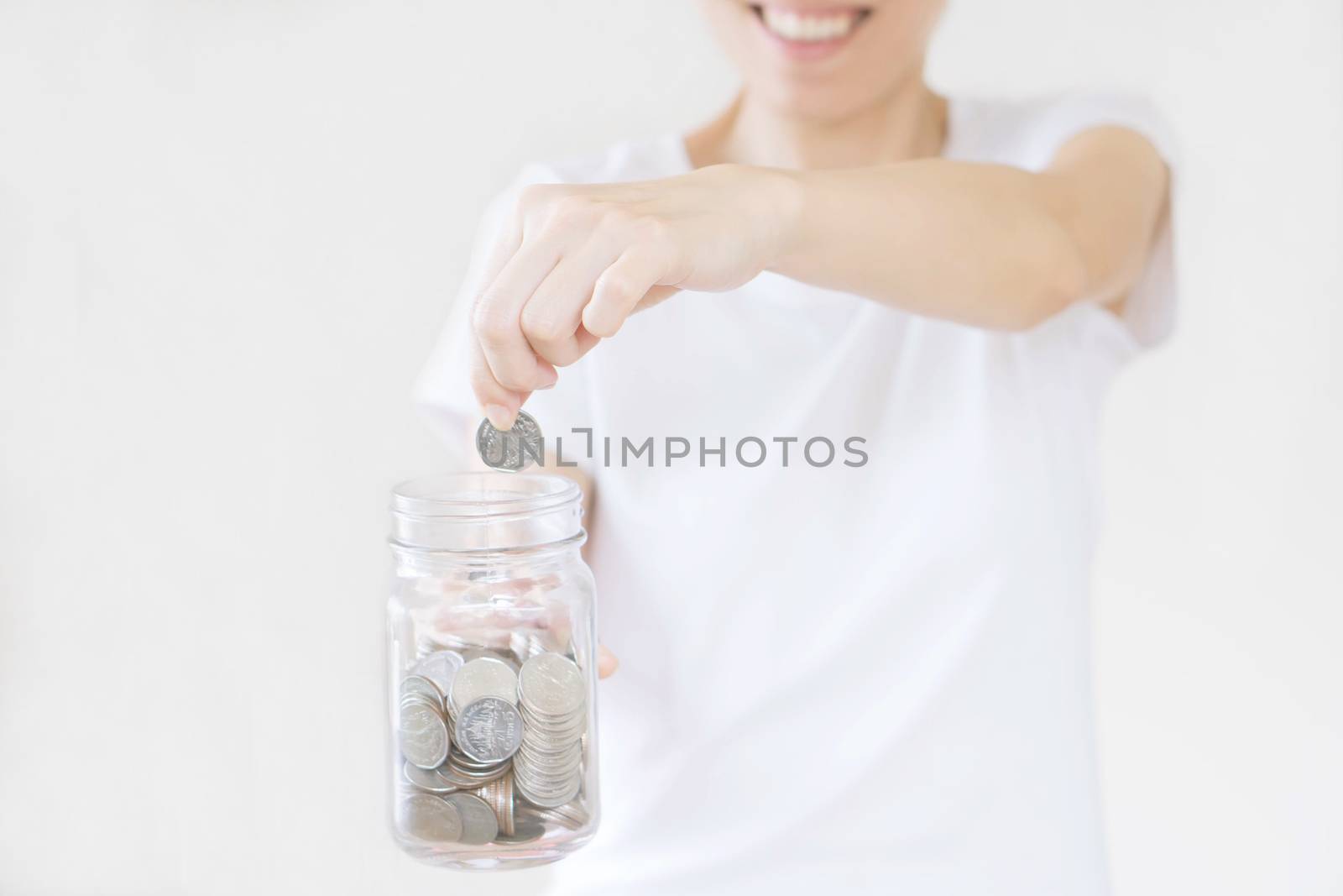 business, finance, saving, banking and people concept - close up of woman hands putting us dollar money into glass mason jar