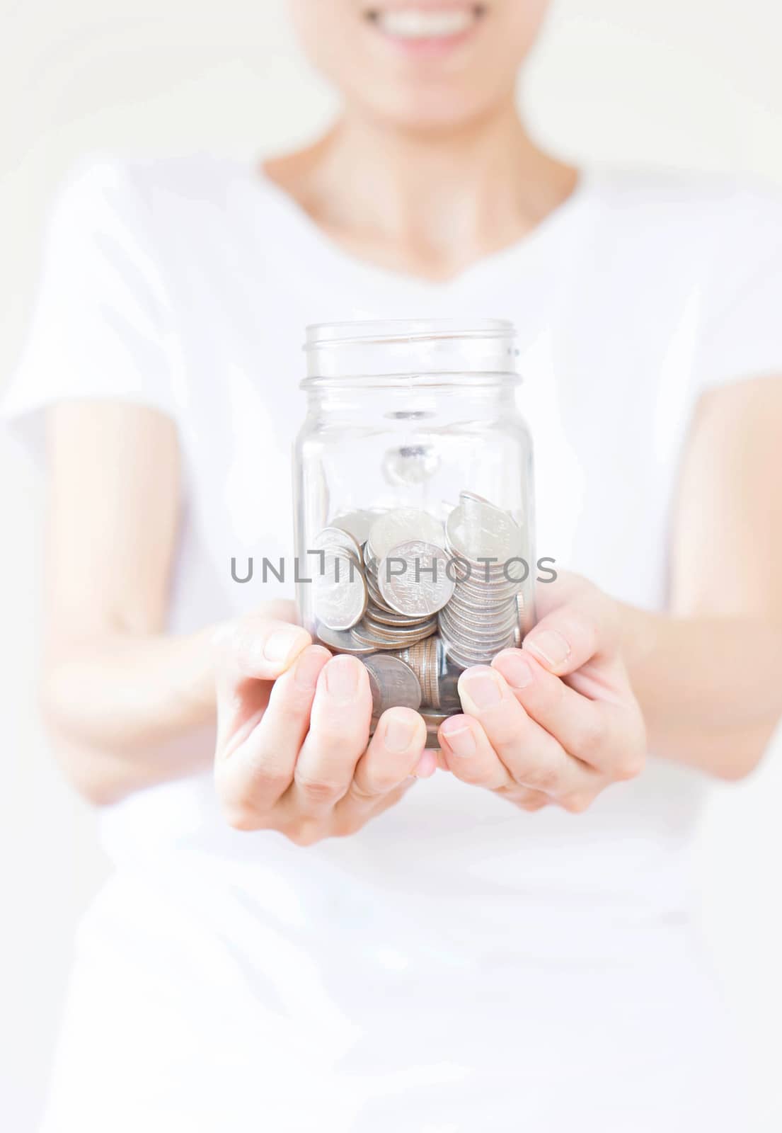 Woman holding money jar with coins close up by ekachailo