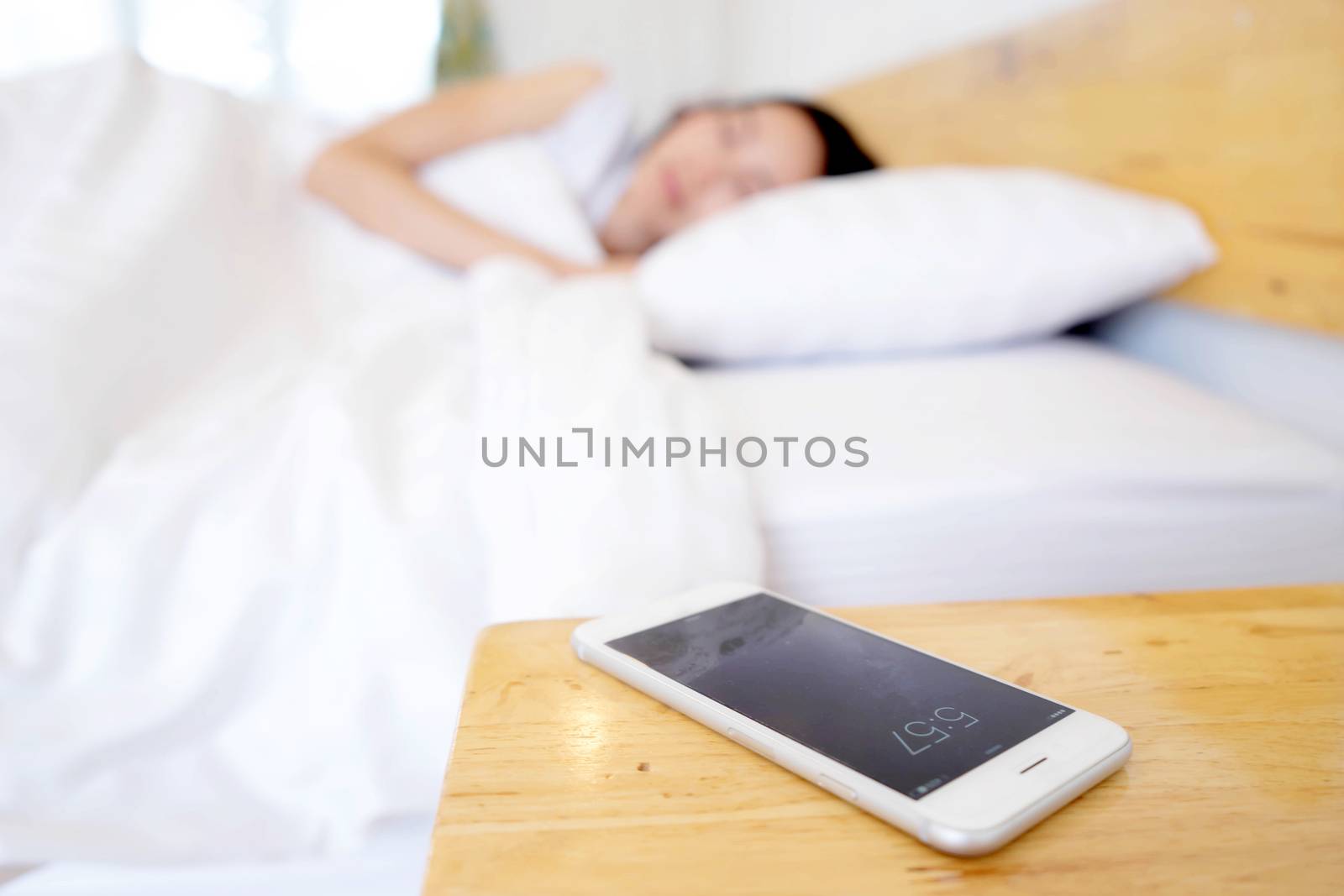 Sleeping Woman Being Woken By Mobile Phone In Bedroom by ekachailo