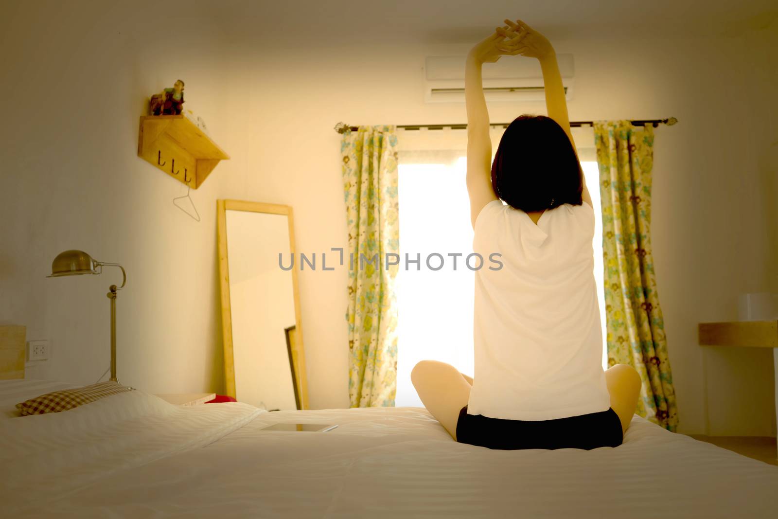 Woman stretching in her bed, rear view
