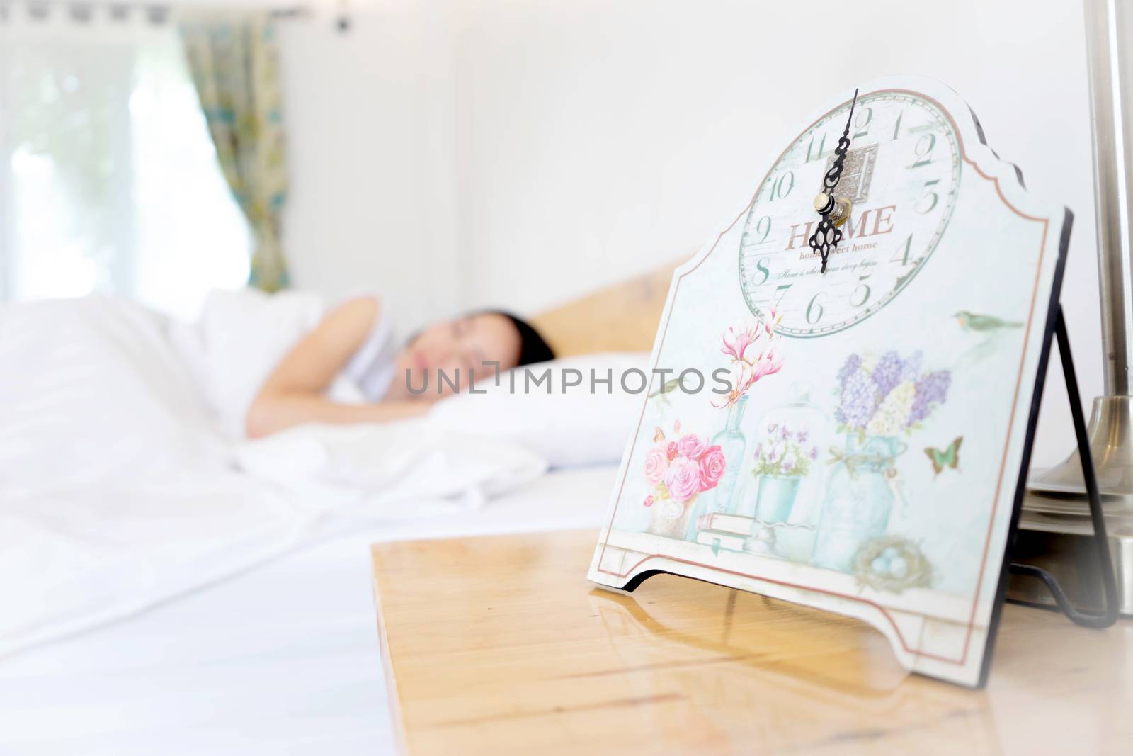Young woman sleeping in bed with alarm at night