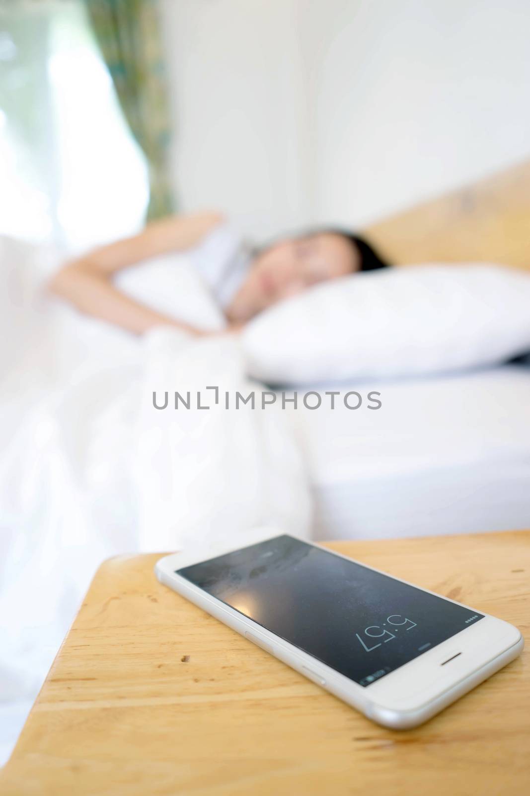 Sleeping Woman Being Woken By Mobile Phone In Bedroom by ekachailo