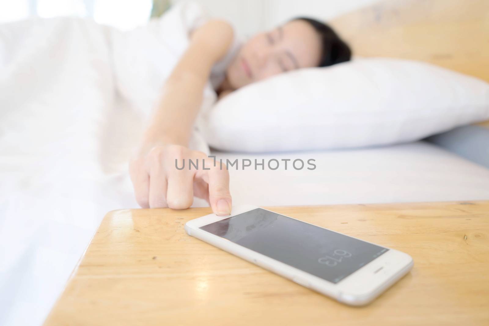 Sleeping Woman Being Woken By Mobile Phone In Bedroom by ekachailo