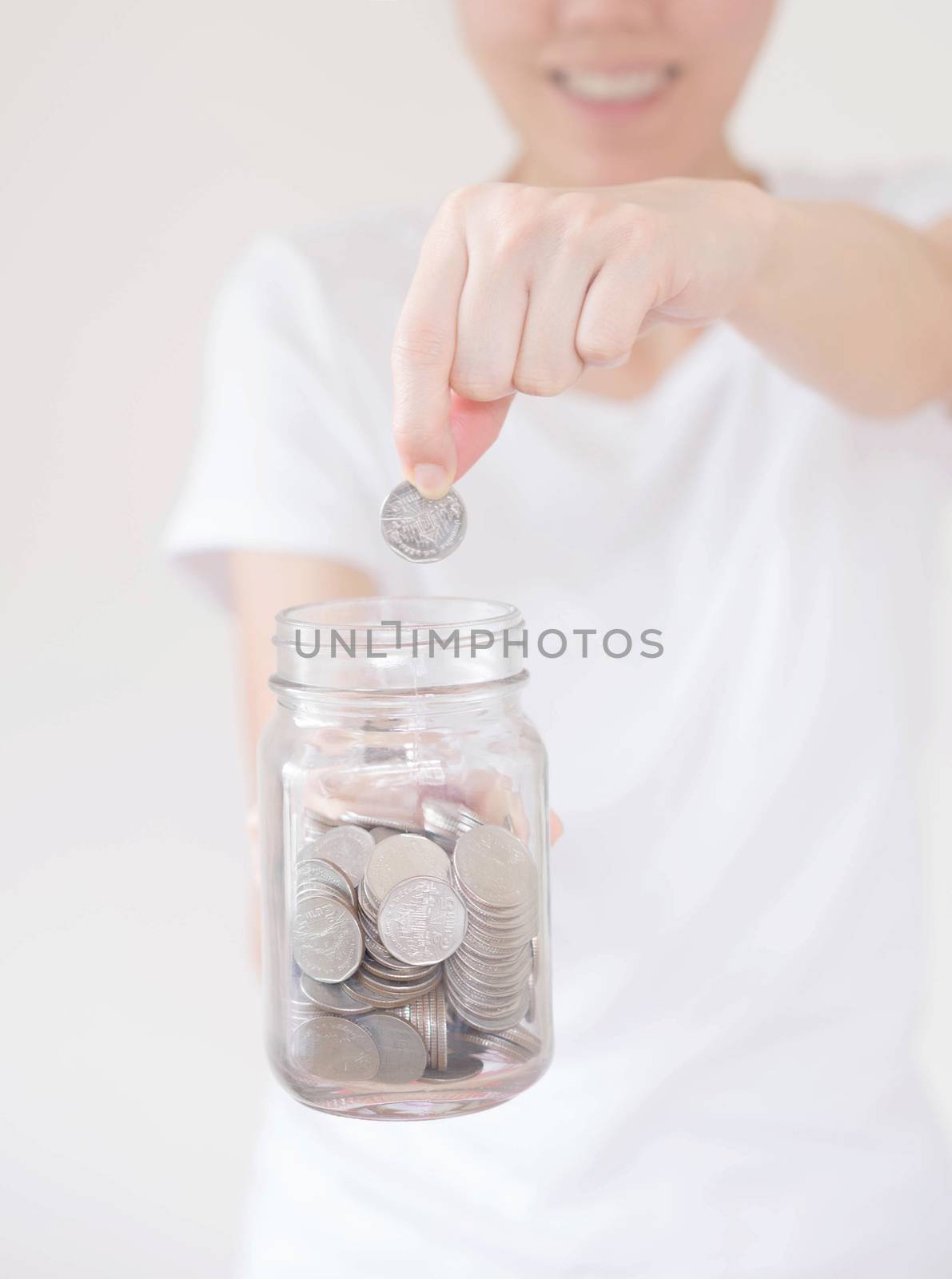 business, finance, saving, banking and people concept - close up of woman hands putting us dollar money into glass mason jar