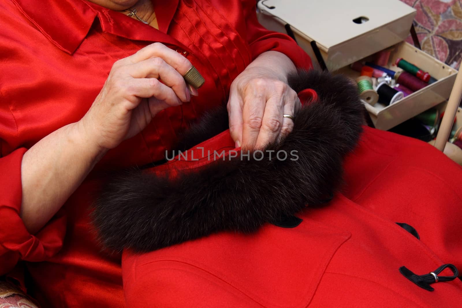 Woman's  hands sewing a red coat