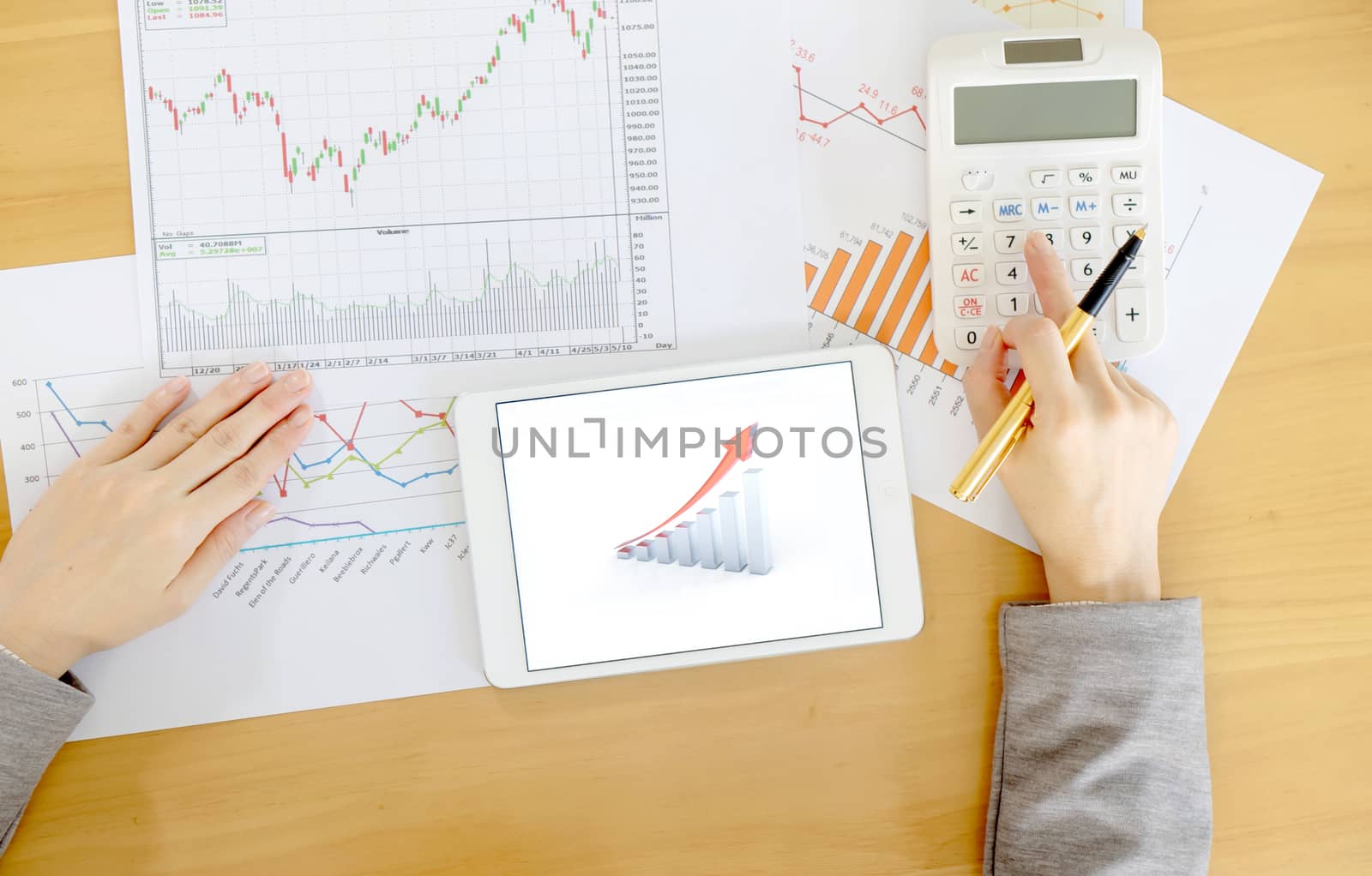 Close-up Of Businesswoman Holding Digital Tablet With Graphs On Desk