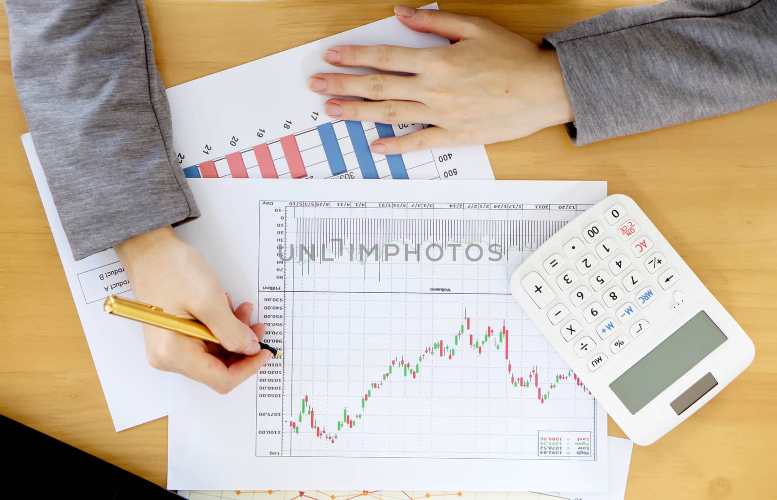 Businesswoman using calculator while analyzing graphs