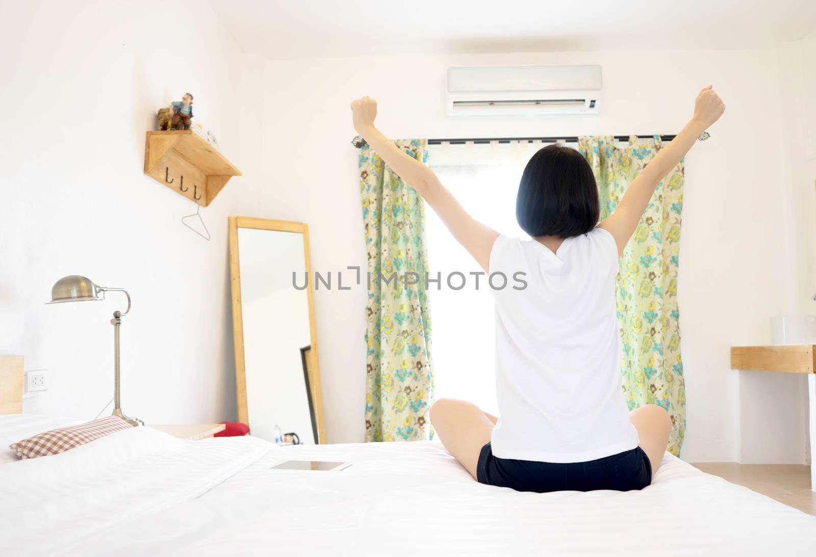 Woman stretching in her bed, rear view